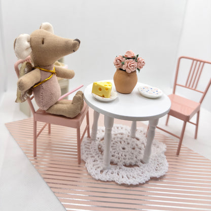 Miniature scene with  mouse, table, chairs, and decorative elements on a white background